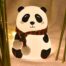 A close-up of a panda-shaped **touch lamp** with eyes closed, made from soft white silicone. The lamp emits a vibrant blue glow.